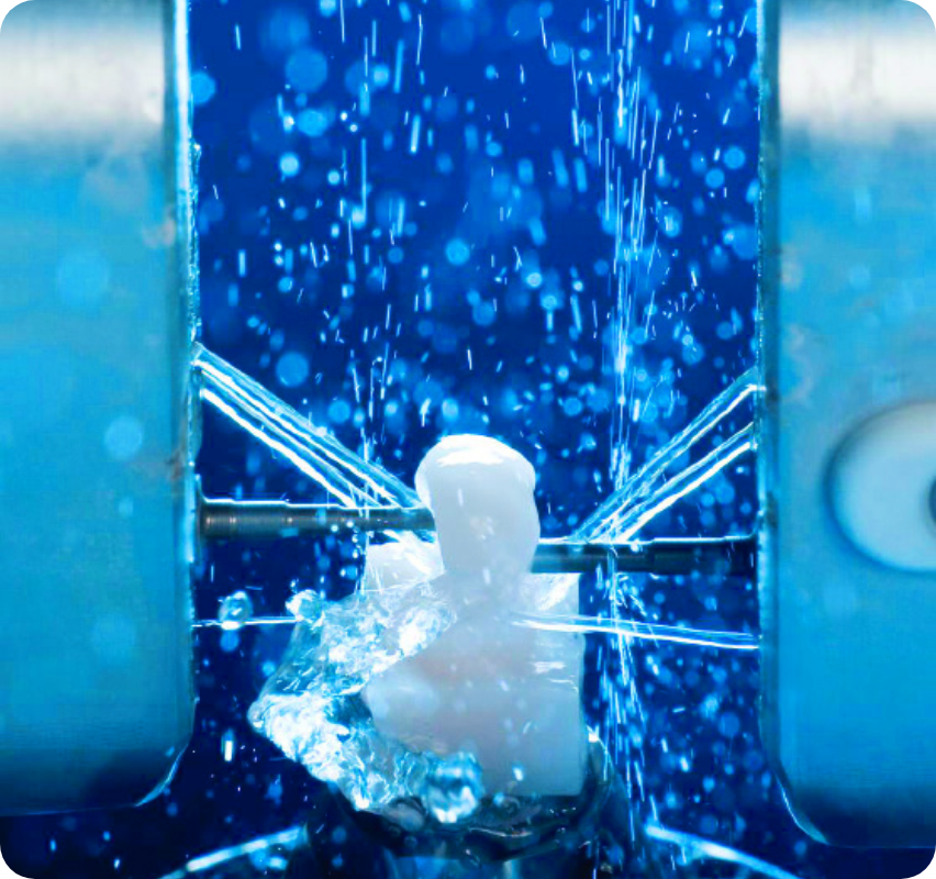 青い液体中で気泡とともに歯の模型が処理されている様子を捉えた、洗浄または化学処理工程のクローズアップ画像